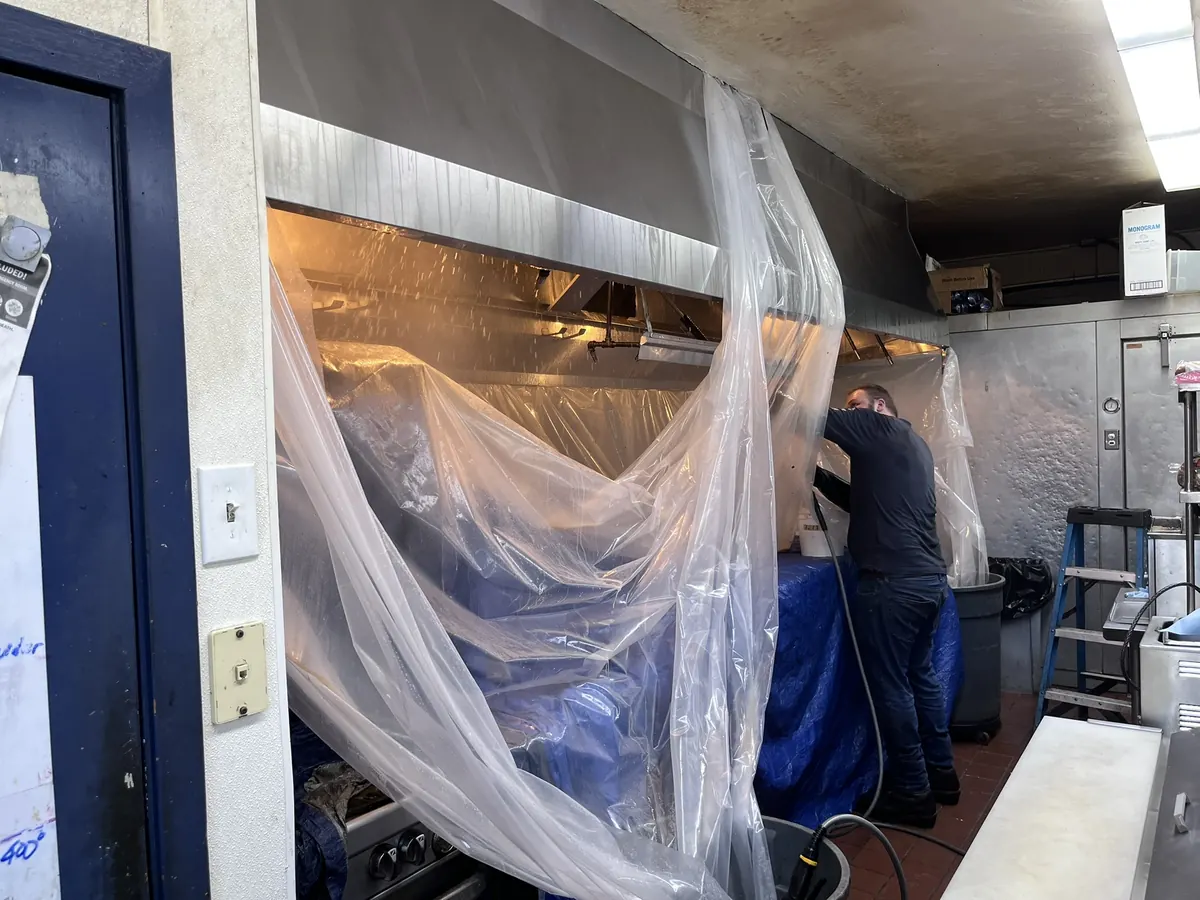 Kitchen hood with equipment wrapped in plastic before cleaning